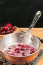 Heated cherries jubilee in copper pan Royalty Free Stock Photo