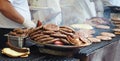 Heated metal tray full of meat specialties from the Serbian and Balkans cuisine. In the background bread, meat on the grill and c