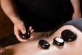 Heated stones on back of woman. Stone massage therapy in spa for relaxing.