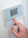 Heating concept. Man is adjusting temperature in room on electronic thermostat control. Royalty Free Stock Photo