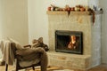 Heating house in winter with wood burning stove. Burning fireplace in rustic living room with cozy chair, rug and firewood stack. Royalty Free Stock Photo