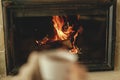 Heating house with wood burning stove. Burning fireplace close up and blurred hands with cup of warm tea , autumn hygge. Relaxing Royalty Free Stock Photo