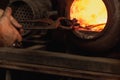 Close-up working powerful hands of male blacksmith making red hot metal in furnace, horn. Work process of heating metal