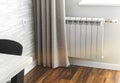 Heating metal radiator, white radiator in modern apartment interior with wooden floor