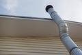 Heating pipe under the roof of a house covered with siding against the sky Royalty Free Stock Photo