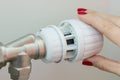 Heating radiator in an apartment. The female hand on the thermostat regulates the temperature. Royalty Free Stock Photo