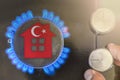 Heating season or gas use in Turkey. Concept, model of a house stands near the flame of a gas boiler on a black