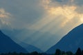 Heavenly golden light rays shining through clouds down to valley and mountains Royalty Free Stock Photo
