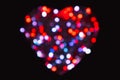 Heavily blurred from the bokeh effect red, white and blue circles of light in the shape of a heart on a black background Royalty Free Stock Photo