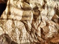 Heavily crumpled textured kraft paper with a black smooth insert in sunlight and with shadows. Abstract background Royalty Free Stock Photo
