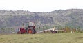 Heavily used red old tractor working on the field Royalty Free Stock Photo