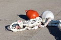 Heavily used small dilapidated white plastic buoys held together by strong rope left to dry on concrete pier