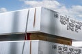 Heavy aluminum bars stacked on top of each other in an aluminum smelting plant, against the blue sky.