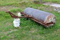 Heavy barrel like weight with strong rusted metal frame used for flattening sport terrein surrounded with uncut grass