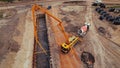 Heavy big machinery during road works. A yellow crane filling up a long hole with fresh cement.