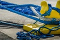 Heavy blue ropes wrap around a yellow mooring bollard on a pier