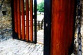 Heavy brown wooden fortress gate in half open position and stone wall .drawbridge beyond