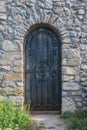 Heavy closed door on a stone wall of medieval fortress, made riveted wood