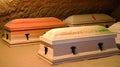 Heavy coffins lie on sand floor in an very small old dusty cemetery crypt in a cave