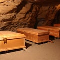 Heavy coffins lie on sand floor in an very small old dusty cemetery crypt in a cave