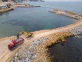 Heavy construction equipment is building a breakwater. Pouring concrete on a pier under construction in the sea. Royalty Free Stock Photo