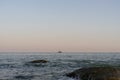 A heavy container ship with cargo enters the port by tug. Port of Yuzhny. Coastal stones in the foreground. Selective focus. 2019.