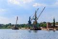 Heavy cranes in cargo port on riverbank