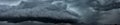 Heavy, dark clouds build in to a huge rain storm over city, panorama format Royalty Free Stock Photo