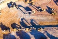 Heavy dump trucks, bulldozers, and excavators on yellow clay construction site. Long shadows on the ground. Top view at sunset Royalty Free Stock Photo
