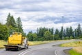 Heavy duty big rig semi truck tractor transporting oversized cargo on step down semi trailer turning on the round highway entrance Royalty Free Stock Photo