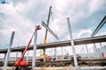 Heavy duty industrial crane operating on construction site, building concrete hall with prefabricated beams