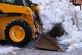 Heavy duty earth mover cleaning snow off the sidewalks after blizzard