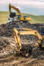 Heavy duty excavators loading dumper trucks with garbage and urban trash Royalty Free Stock Photo