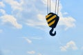 Heavy duty hooks on ropes with yellow-black guides in front of a white-blue sky with clouds Royalty Free Stock Photo