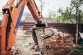 Industrial backhoe excavator and bulldozer demolishing old house and ruins