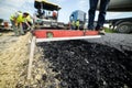 Heavy duty road building. Hot Asphalt being laid and measured fo