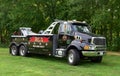 A heavy duty tow truck or wrecker sits on the grass in rural NH