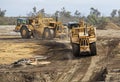 Heavy earthmoving equipment including scapers and motor graders involved in grading operations