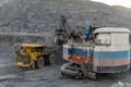 A heavy electric excavator loads ore into a dump truck.