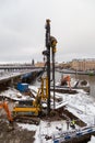 Heavy equipment drilling a pile for building foundations on a snowy day by the water