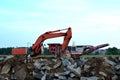 Heavy excavator working at construction site. Unloading old stone or concrete waste into a mobile cheek crusher for crushing Royalty Free Stock Photo