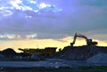 Heavy excavator working in quarry on a background of sunset and blue sky.