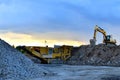 Heavy excavator working in quarry on a background of sunset and blue sky.