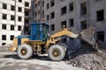 Heavy forklift front loader is working on the reconstruction of an old residential house