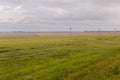 Heavy grey clouds in the cold autumn sky over green fields, trees, forests, streams. Before storm. Electric poles Royalty Free Stock Photo