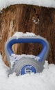 Gym kettlebell weight in a snow, with copy space on wooden background.