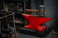 A heavy hammer stands on an anvil in the forge.