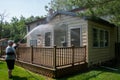 Heavy husband power washing the siding on the back of a house over a brown wooden deck.