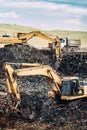 Heavy industrial machinery, excavators digging and loading dumper trucks Royalty Free Stock Photo