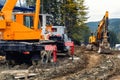 Heavy industrial machinery vehicles working in mud dirt bog road on top of mountain peak resort in forest. Crane and Royalty Free Stock Photo